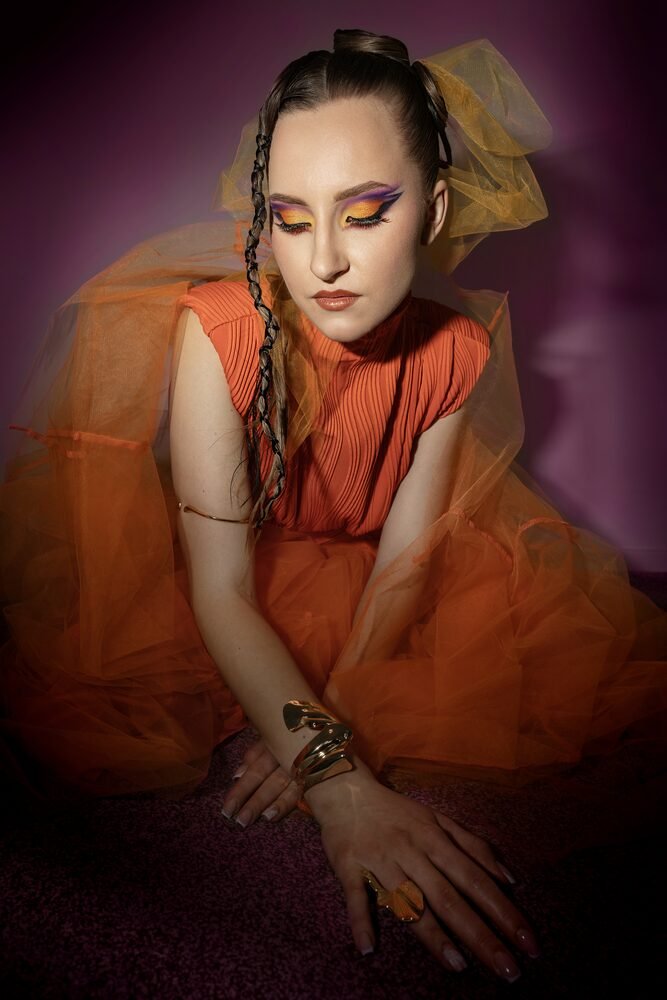 Editorial makeup with orange tulle styling and graphic eyes
