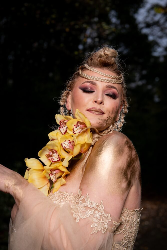 Editorial makeup with gold body art and orchid styling