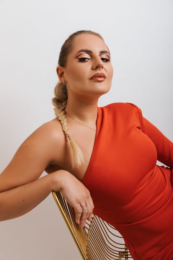 Editorial makeup styled with a red dress and gold fan