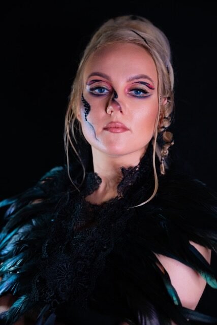 Blue graphic eye makeup styled with black feathers